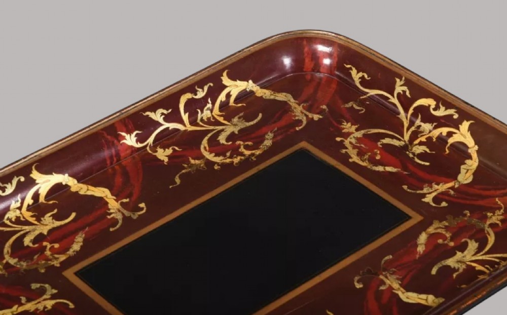 A rectangular Regency papier-mache tray with rounded edges, featuring gilded foliage and red swirl decoration surrounding a central black panel. View IV