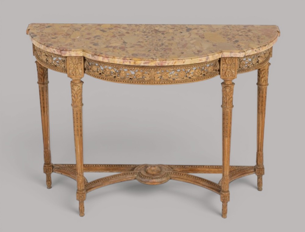 An 18th-century Louis XVI demilune console table featuring a variegated marble top, pierced carved floral frieze, fluted tapered legs, and a decorative central stretcher.