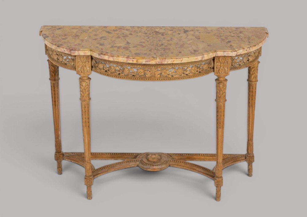 An 18th-century Louis XVI demilune console table featuring a variegated marble top, pierced carved floral frieze, fluted tapered legs, and a decorative central stretcher. View VII