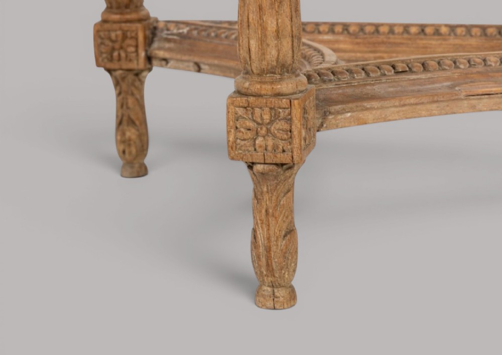 An 18th-century Louis XVI demilune console table featuring a variegated marble top, pierced carved floral frieze, fluted tapered legs, and a decorative central stretcher. View VIII