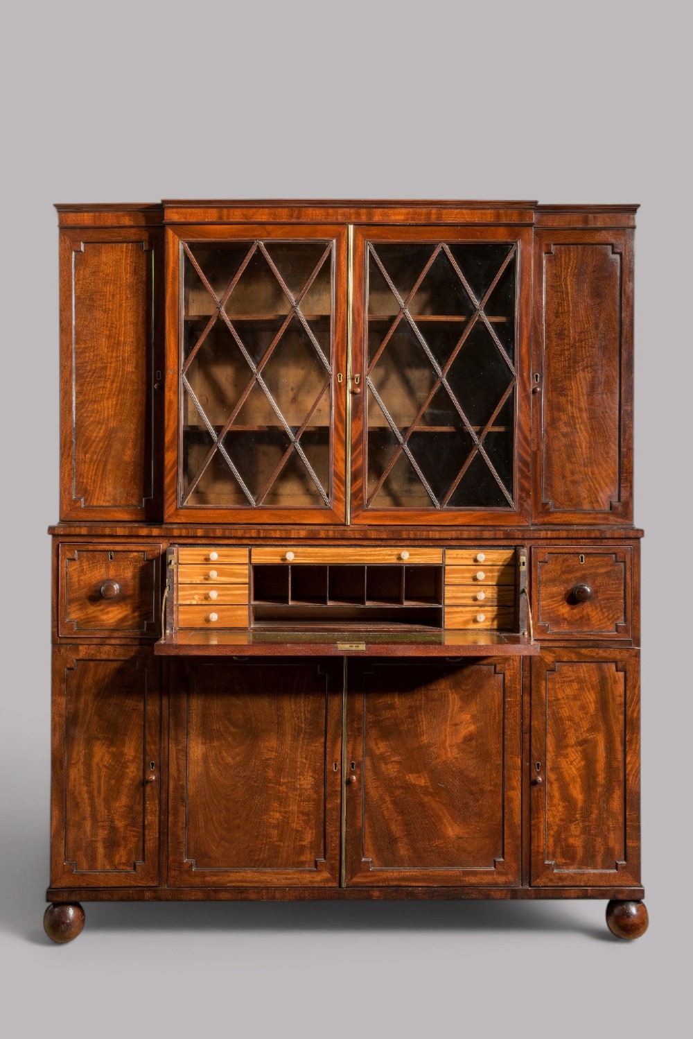 A pair of Regency mahogany library bookcases with diamond astragal glazed upper doors and panelled lower cupboard doors. View II