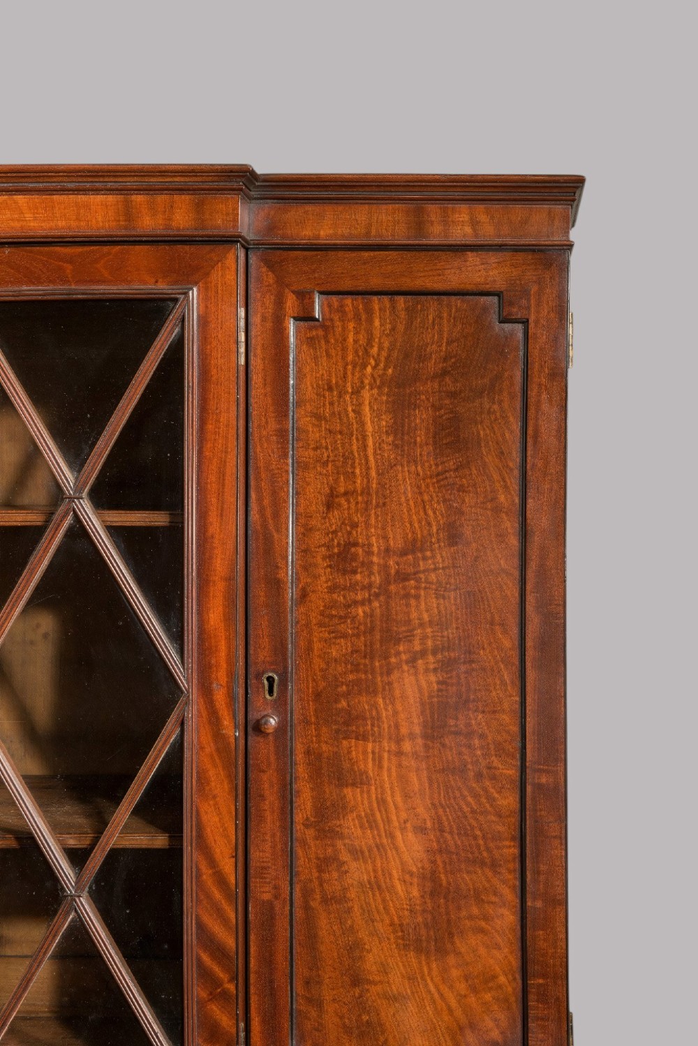 A pair of Regency mahogany library bookcases with diamond astragal glazed upper doors and panelled lower cupboard doors. View V