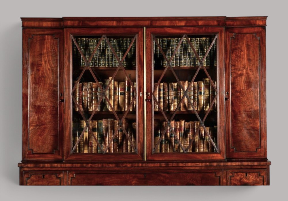 A pair of Regency mahogany library bookcases with diamond astragal glazed upper doors and panelled lower cupboard doors. View X