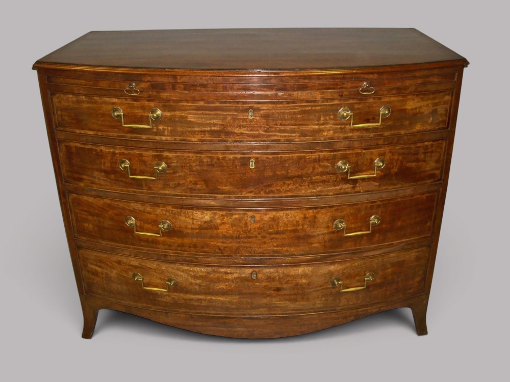 A George III mahogany bowfront chest of drawers featuring four graduated drawers with brass handles and splay feet.