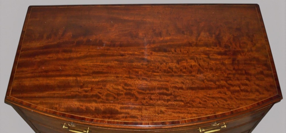 A George III mahogany bowfront chest of drawers featuring four graduated drawers with brass handles and splay feet. View III
