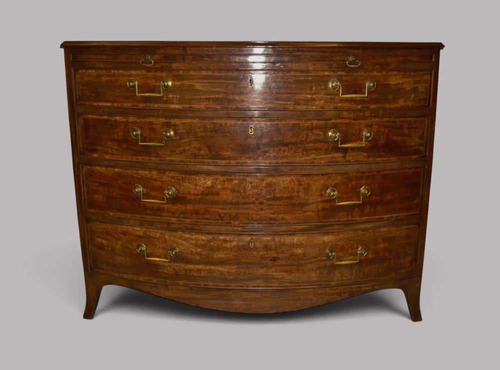 A George III mahogany bowfront chest of drawers featuring four graduated drawers with brass handles and splay feet. View V