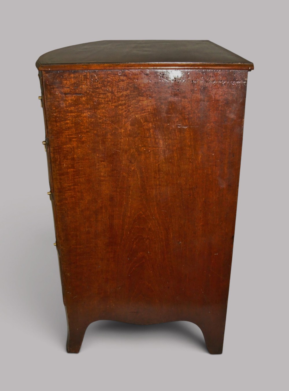 A George III mahogany bowfront chest of drawers featuring four graduated drawers with brass handles and splay feet. View VII