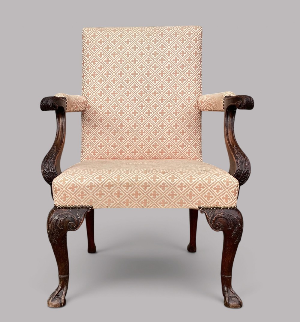 An 18th-century style George II mahogany open armchair upholstered in a cream and red geometric patterned fabric with carved cabriole legs.