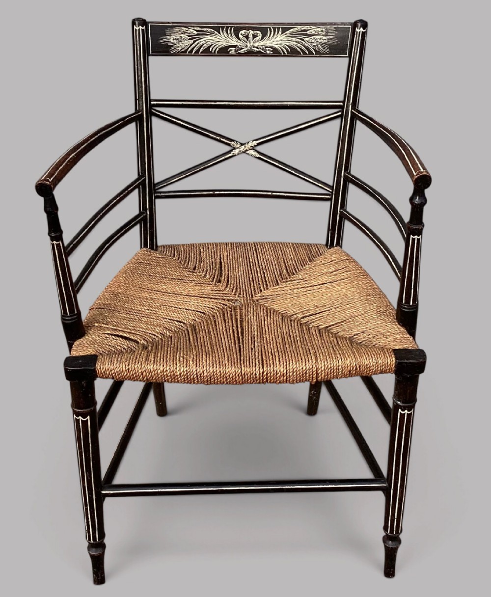 A Regency dark-painted wooden elbow chair featuring hand-painted white line decoration, an X-back splat, and a woven rush seat. View II