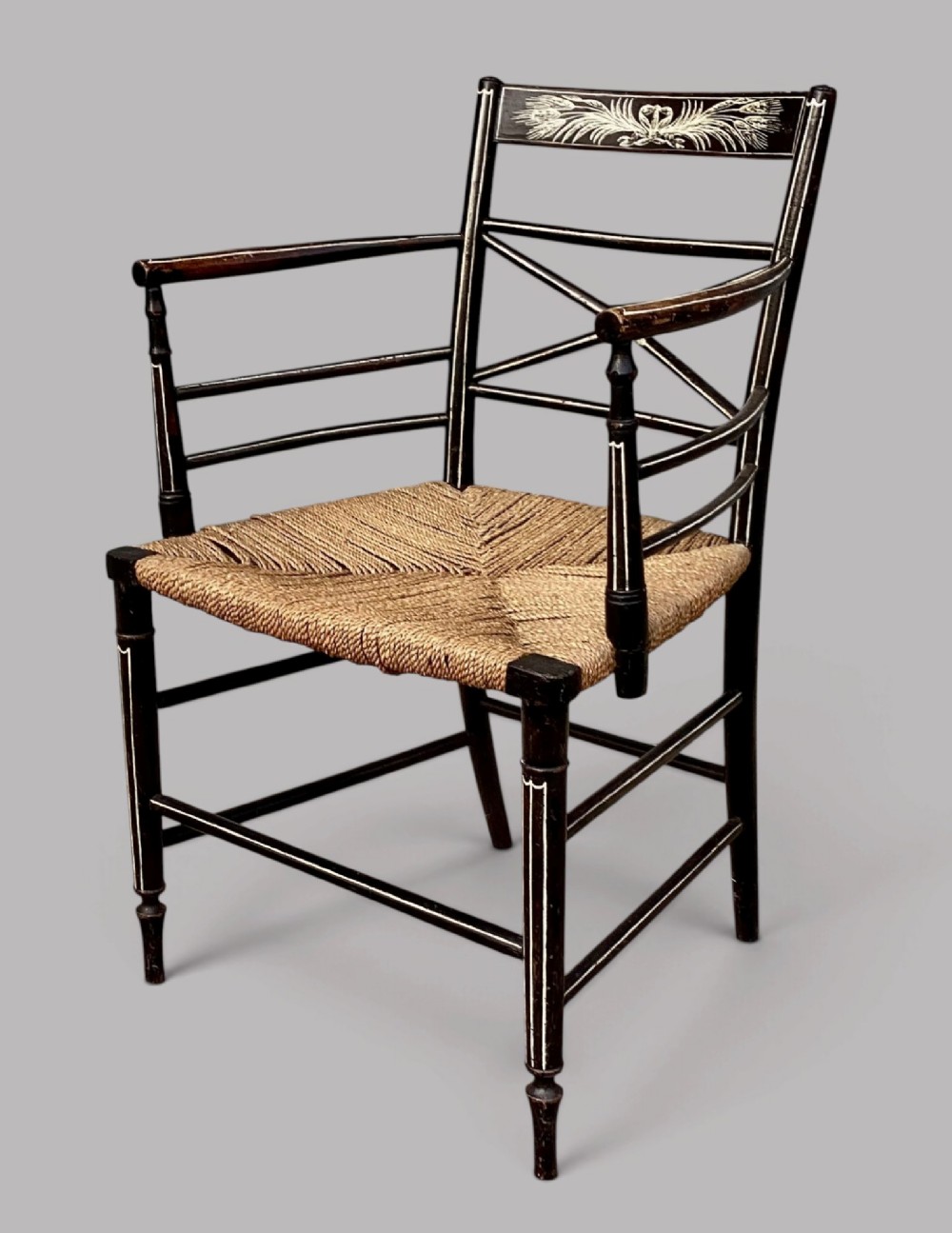 A Regency dark-painted wooden elbow chair featuring hand-painted white line decoration, an X-back splat, and a woven rush seat. View VI