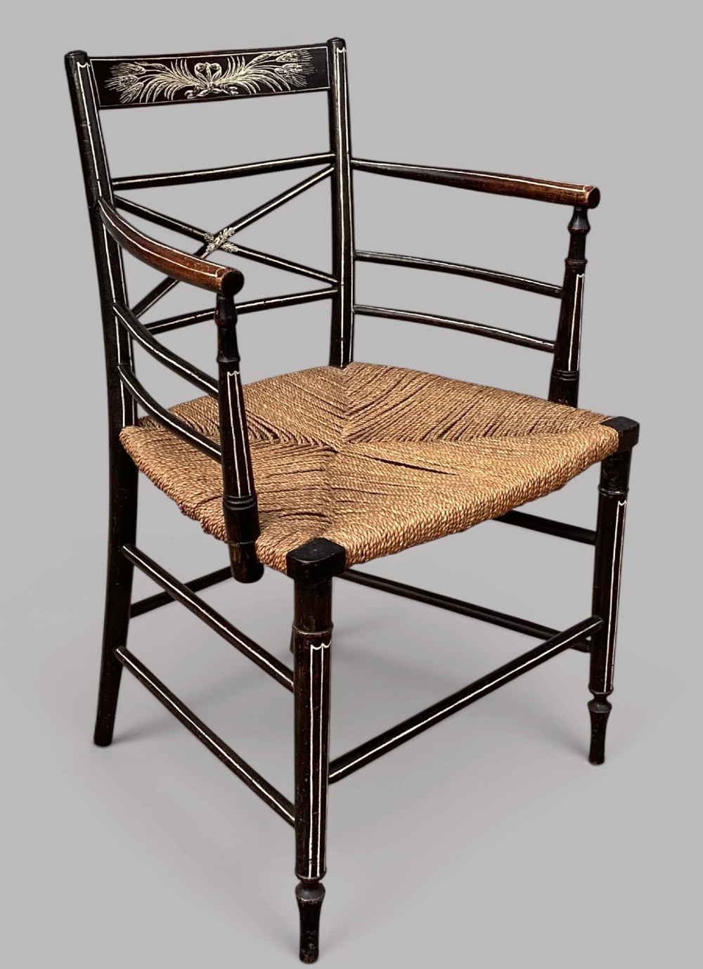 A Regency dark-painted wooden elbow chair featuring hand-painted white line decoration, an X-back splat, and a woven rush seat. View VII