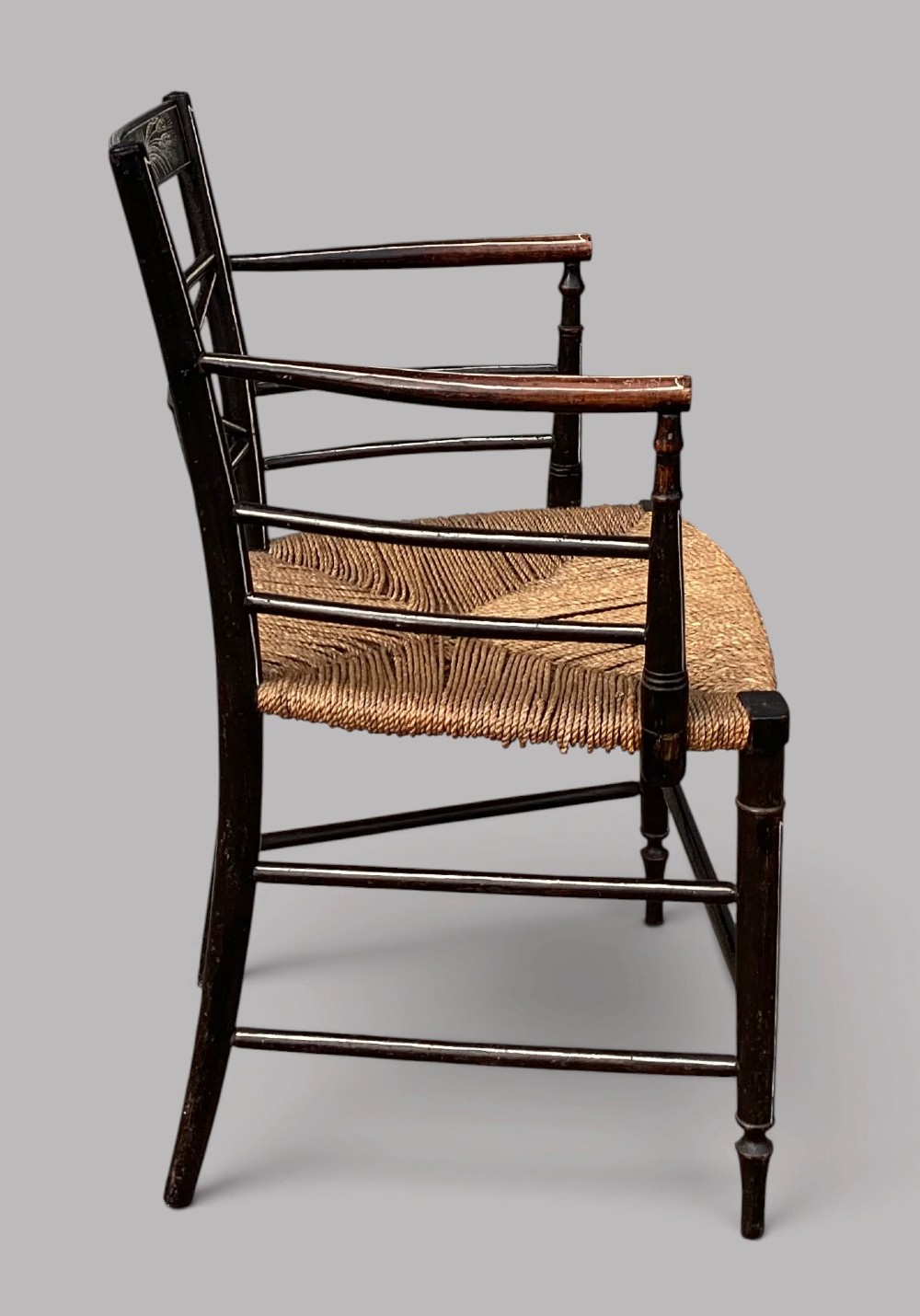 A Regency dark-painted wooden elbow chair featuring hand-painted white line decoration, an X-back splat, and a woven rush seat. View IX