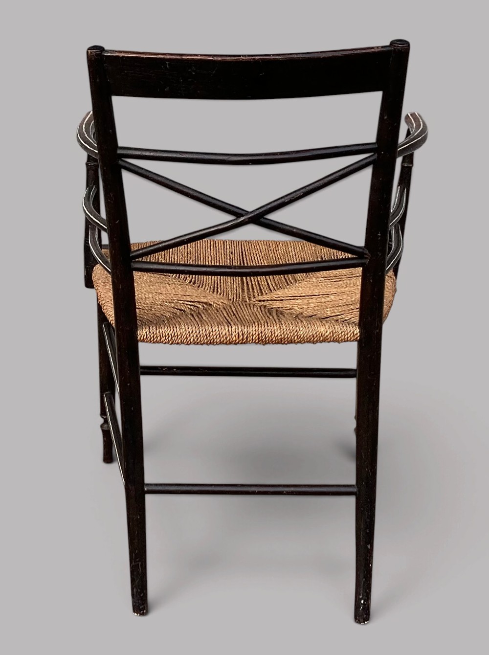 A Regency dark-painted wooden elbow chair featuring hand-painted white line decoration, an X-back splat, and a woven rush seat. View XII