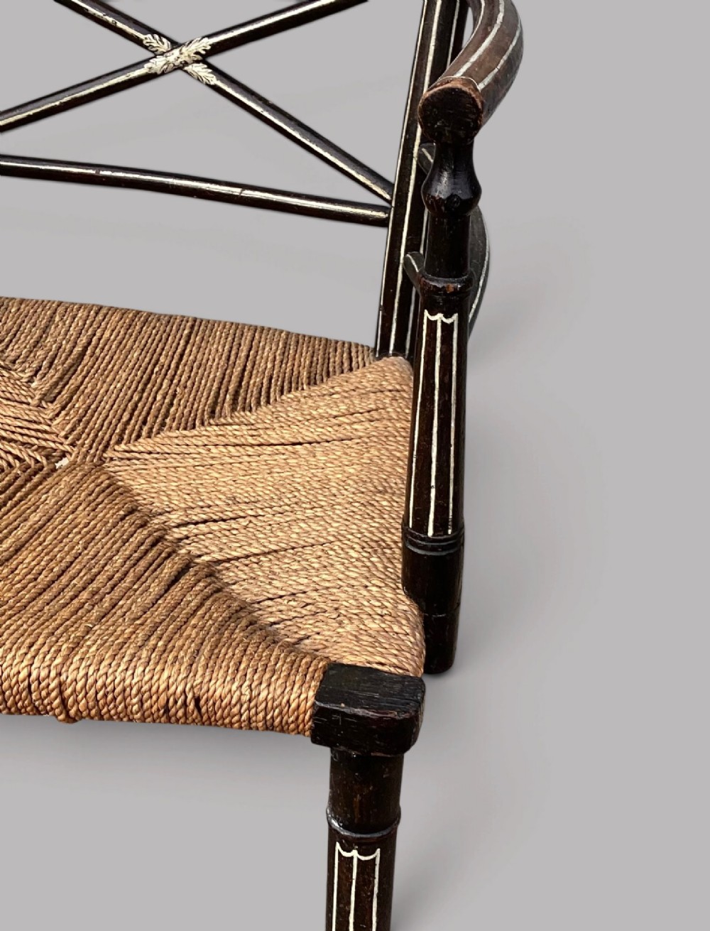 A Regency dark-painted wooden elbow chair featuring hand-painted white line decoration, an X-back splat, and a woven rush seat. View XV