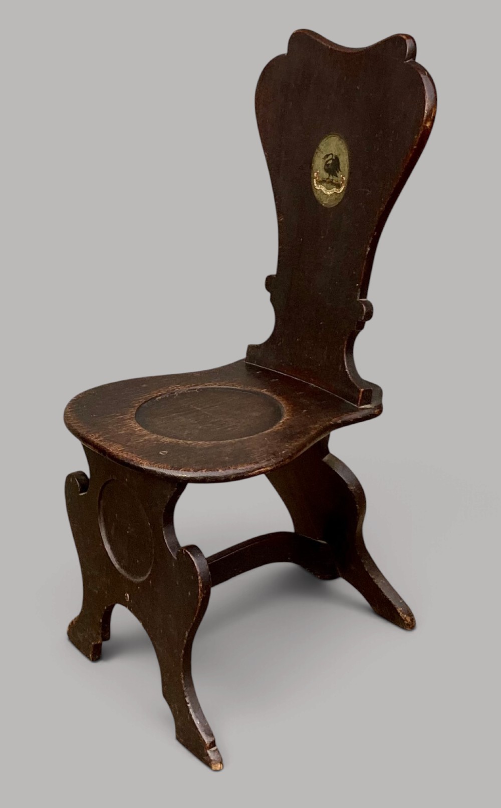 A pair of dark brown 18th-century Irish oak sgabello hall chairs with shaped backs featuring painted armorial crests. View VI