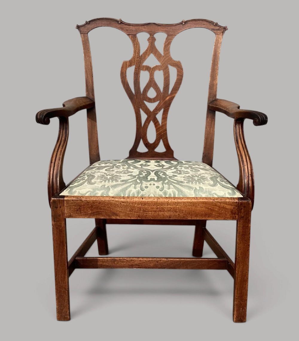 A George III mahogany open armchair featuring a carved pierced back splat, curved armrests, and a patterned fabric seat. View II