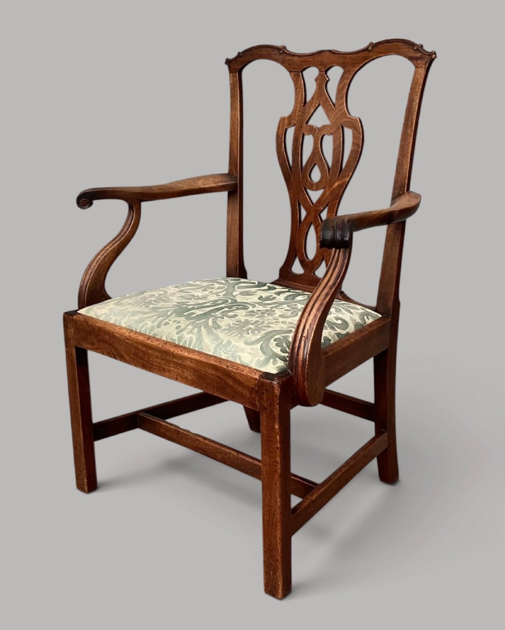 A George III mahogany open armchair featuring a carved pierced back splat, curved armrests, and a patterned fabric seat. View X