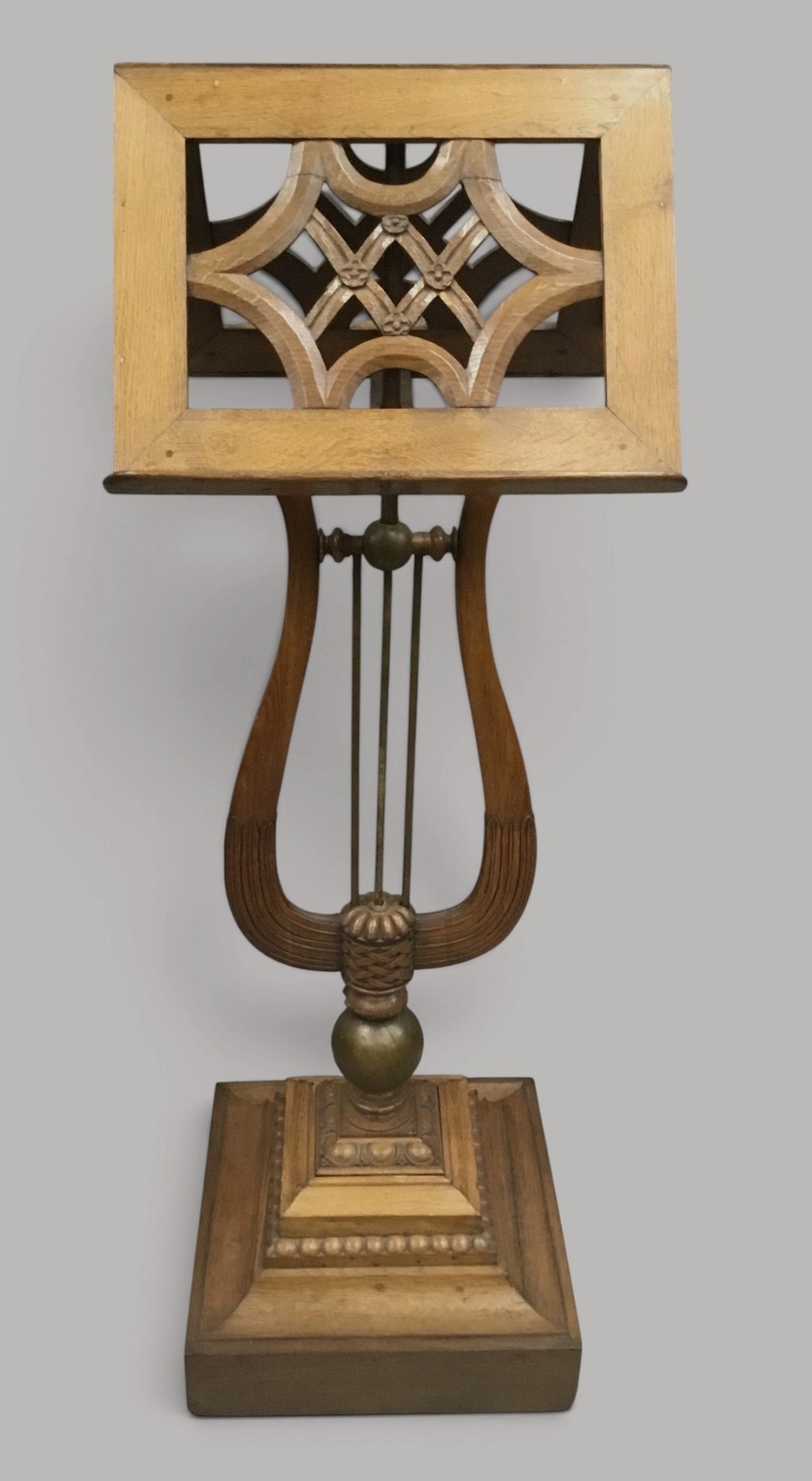 A 19th-century carved oak duet music stand featuring a dual-sided fretwork desk supported by a lyre-shaped stem and a tiered moulded square base.