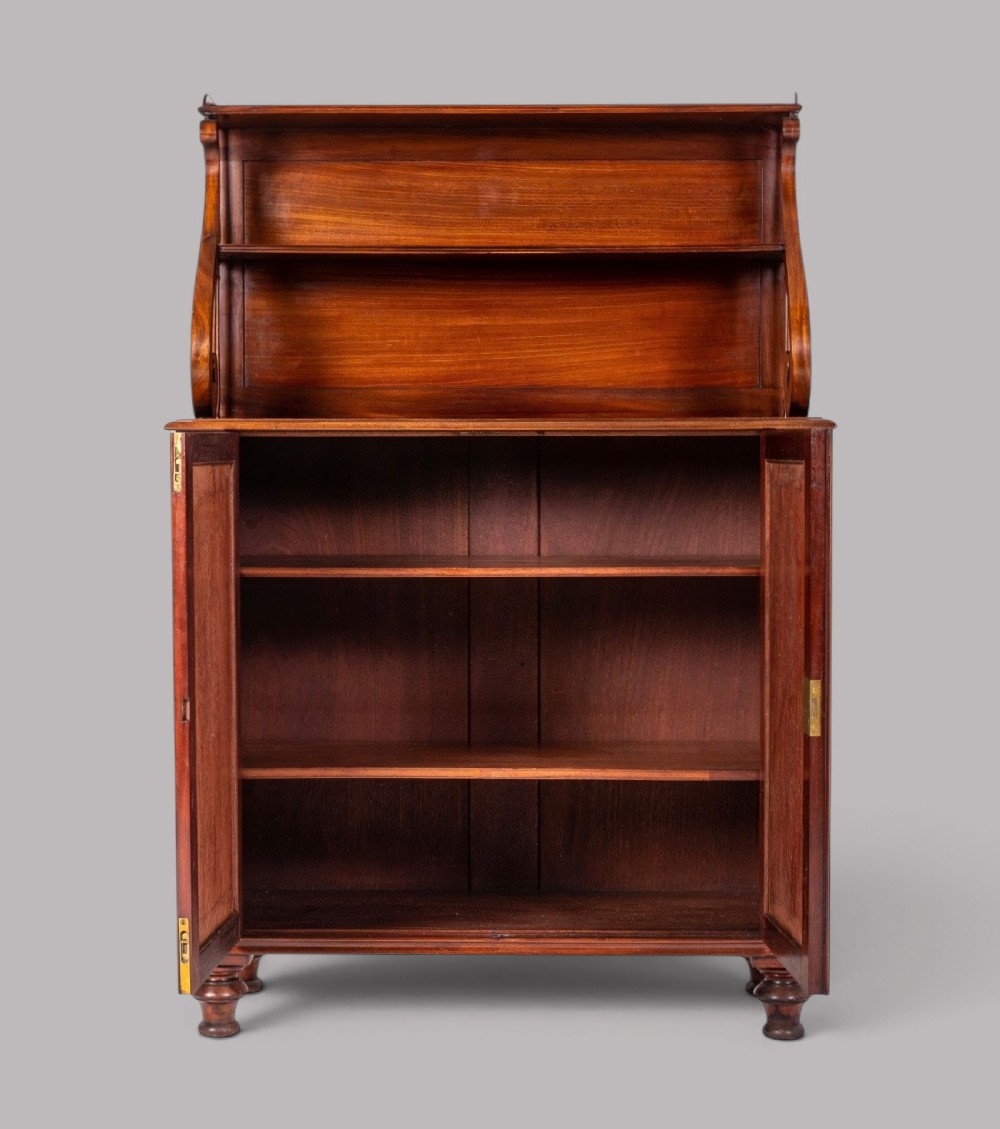 A matching pair of Regency mahogany side cabinets featuring panelled cupboard doors and tiered upper shelves supported by carved scroll uprights. View III