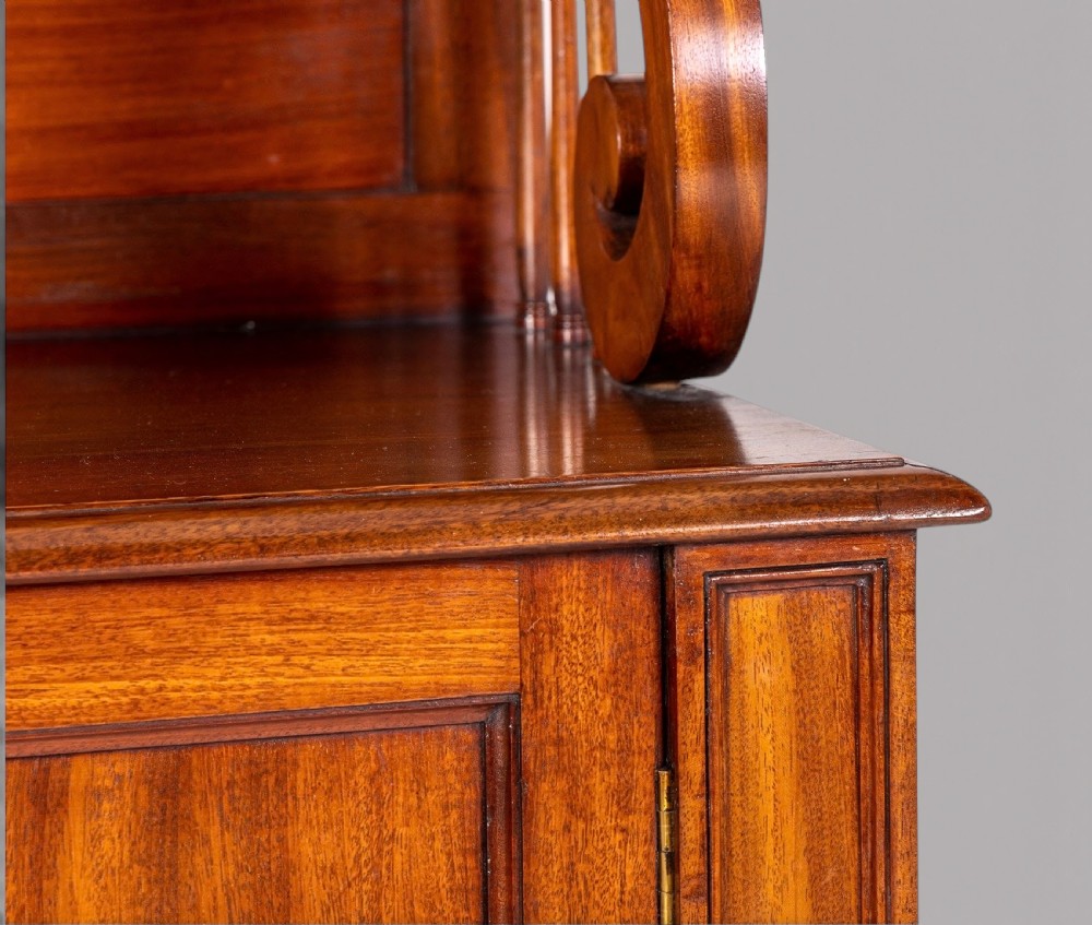 A matching pair of Regency mahogany side cabinets featuring panelled cupboard doors and tiered upper shelves supported by carved scroll uprights. View V