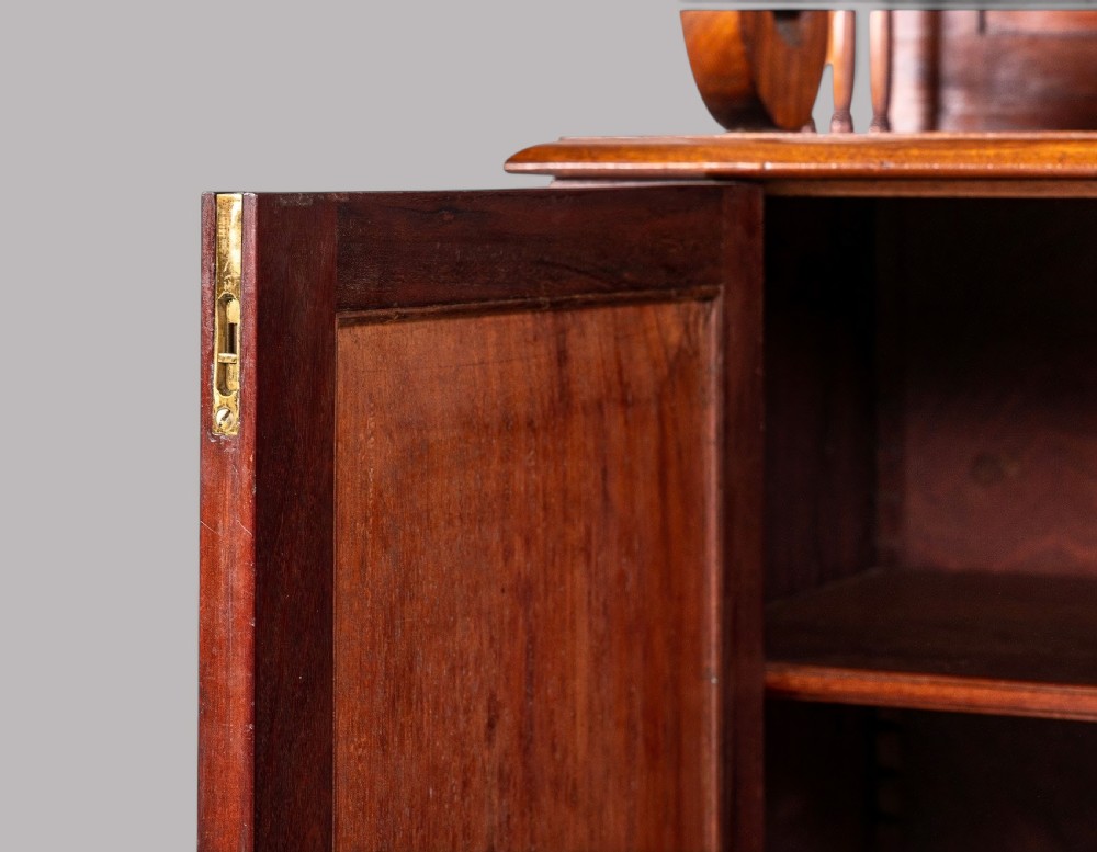 A matching pair of Regency mahogany side cabinets featuring panelled cupboard doors and tiered upper shelves supported by carved scroll uprights. View VII