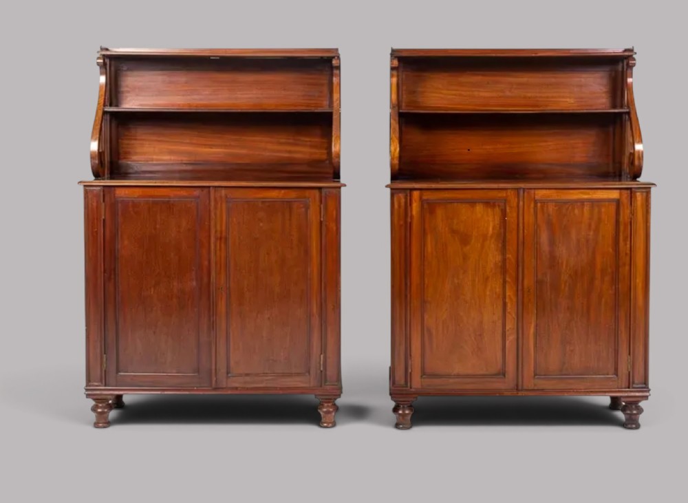 A matching pair of Regency mahogany side cabinets featuring panelled cupboard doors and tiered upper shelves supported by carved scroll uprights. View IX