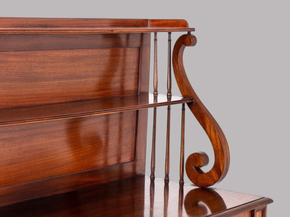 A matching pair of Regency mahogany side cabinets featuring panelled cupboard doors and tiered upper shelves supported by carved scroll uprights. View X