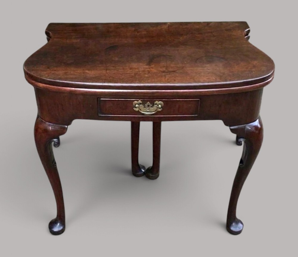 A George II dark mahogany kidney-shaped folding card table featuring cabriole legs with pad feet and a single central drawer with a brass handle.