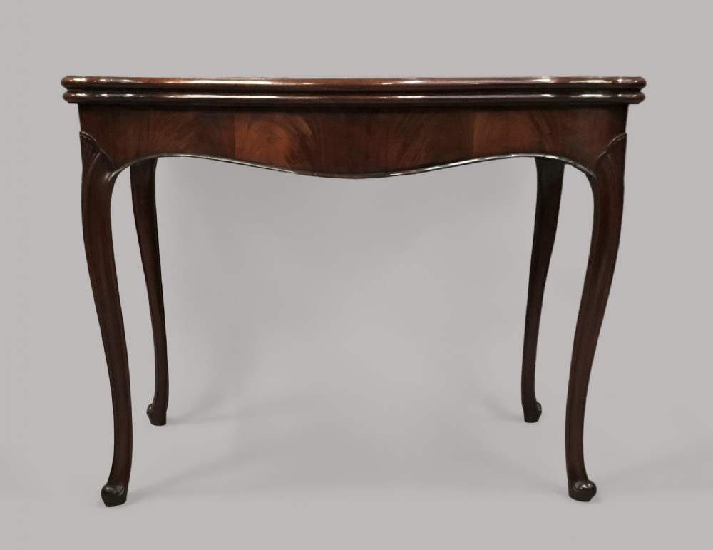 A George III mahogany Hepplewhite card table featuring a serpentine apron, shaped cabriole legs, and a hinged fold-over top.
