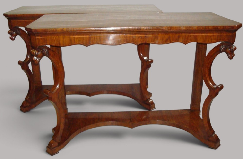 A pair of 19th-century Italian walnut console tables featuring carved zoomorphic legs, serpentine aprons with light string inlay, and lower curved stretchers.