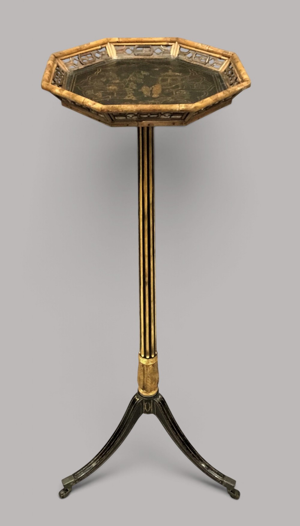 A tall Regency period octagonal torchere stand featuring a black and gold lacquered tray top, reeded column, and tripod base.