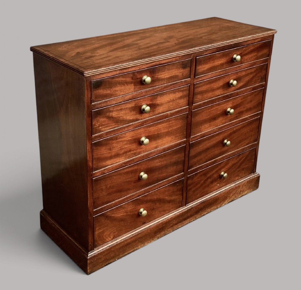 A George III mahogany chest of drawers with ten brass-knobbed drawers configured in two vertical columns on a solid plinth base.