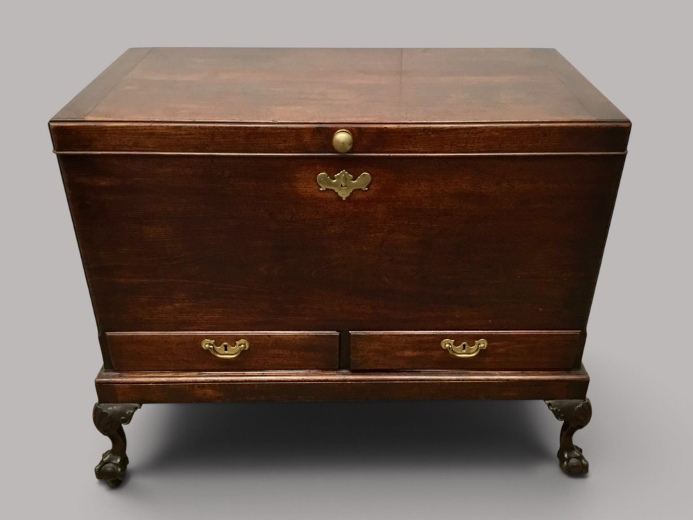 A dark mahogany George II silver chest on stand featuring two lower drawers, brass handles, a central keyhole escutcheon, and carved cabriole legs.