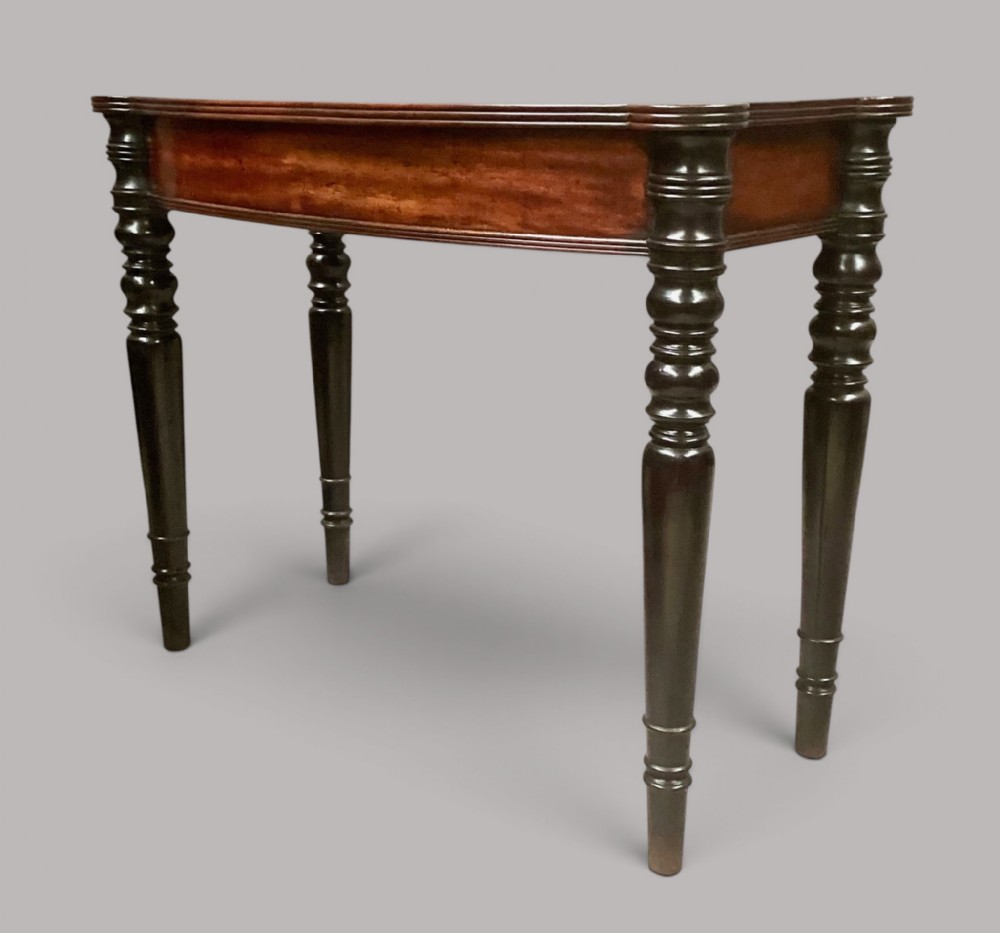 A George IV mahogany bowfront side table with a curved front apron and four turned ebonised legs.