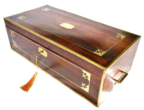 fig 3. An open antique mahogany writing slope featuring a red gold-tooled leather writing surface, brass corner mounts, and dedicated compartments for inkwells.