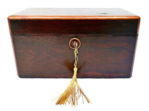 fig 2. An open dark wood William IV tea caddy featuring two internal lidded compartments, a red embossed paper lining inside the lid, and a brass key with a tassel inserted in the lock.