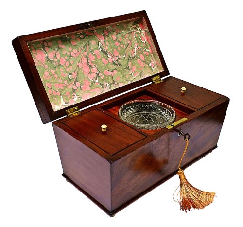 fig 1. An open Victorian mahogany sarcophagus-shaped tea caddy featuring two lidded compartments, a central cut glass mixing bowl, marbled paper lid lining, and a key with a golden tassel.