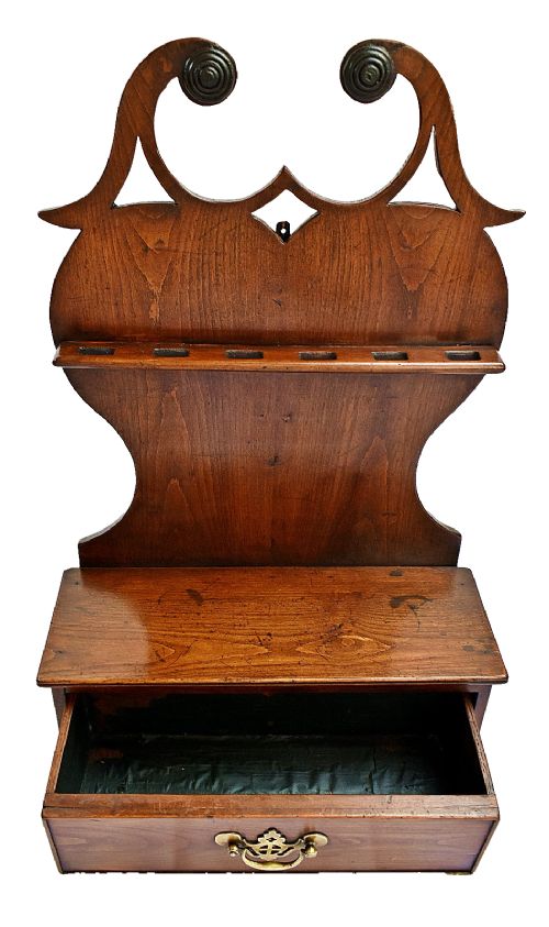 An antique carved oak spoon rack features a shaped scroll crest, a slotted rack, and a lower drawer with a brass drop handle. View V