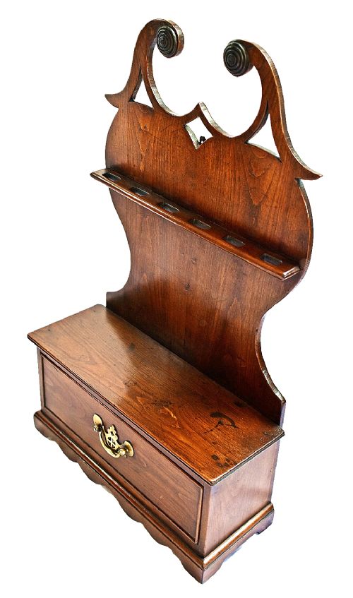An antique carved oak spoon rack features a shaped scroll crest, a slotted rack, and a lower drawer with a brass drop handle. View VII