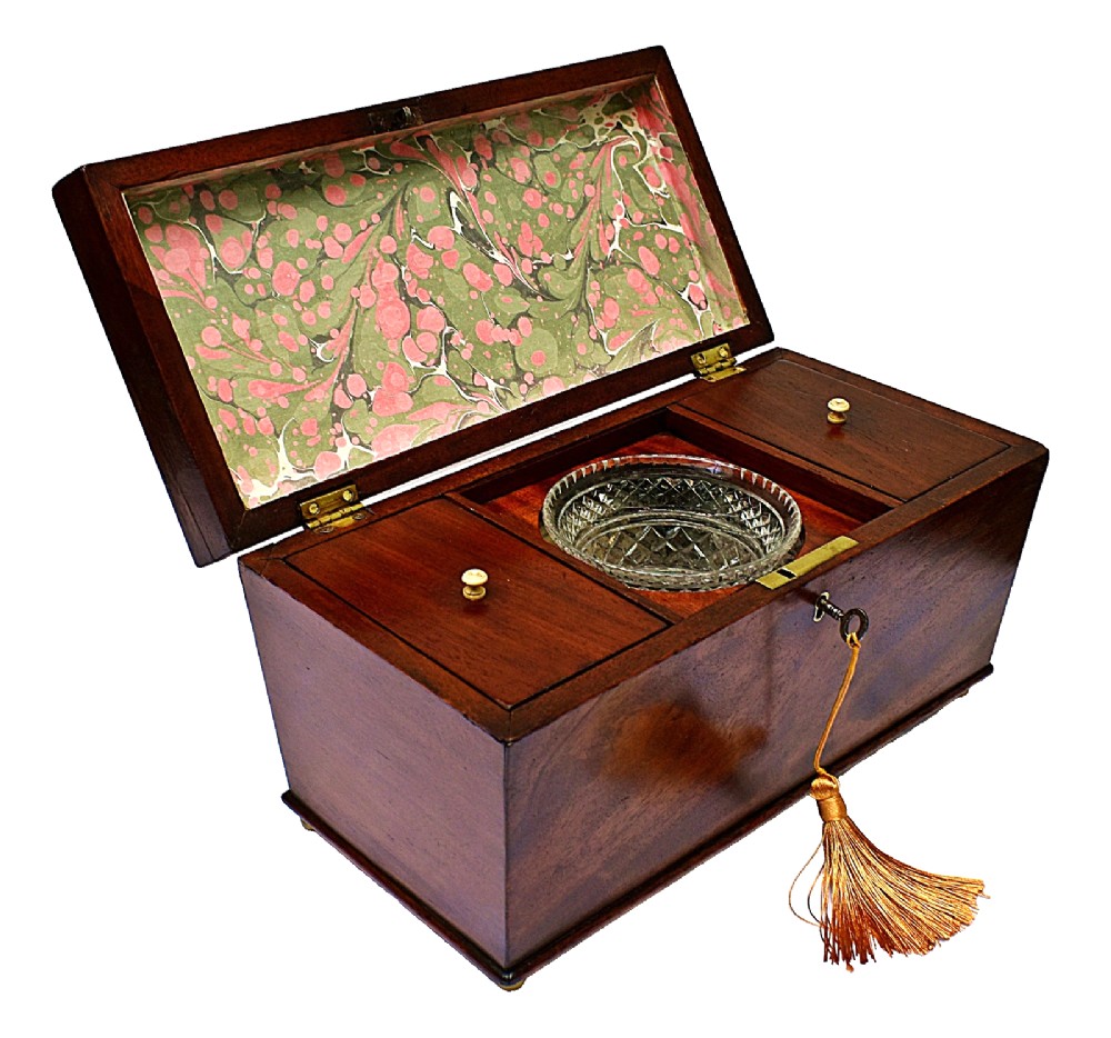 An open Victorian mahogany sarcophagus-shaped tea caddy featuring two lidded compartments, a central cut glass mixing bowl, marbled paper lid lining, and a key with a golden tassel. View II