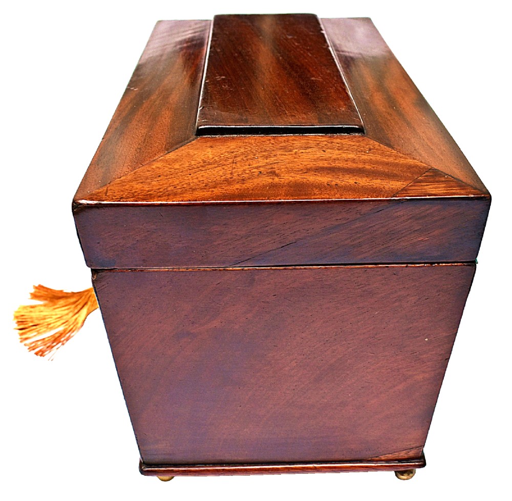 An open Victorian mahogany sarcophagus-shaped tea caddy featuring two lidded compartments, a central cut glass mixing bowl, marbled paper lid lining, and a key with a golden tassel. View VI