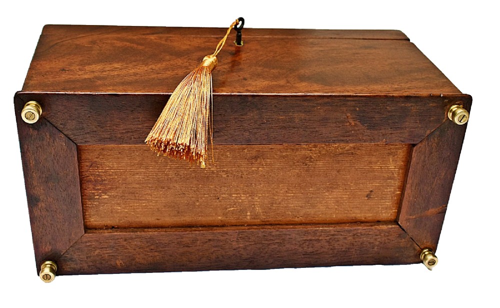 An open Victorian mahogany sarcophagus-shaped tea caddy featuring two lidded compartments, a central cut glass mixing bowl, marbled paper lid lining, and a key with a golden tassel. View XII