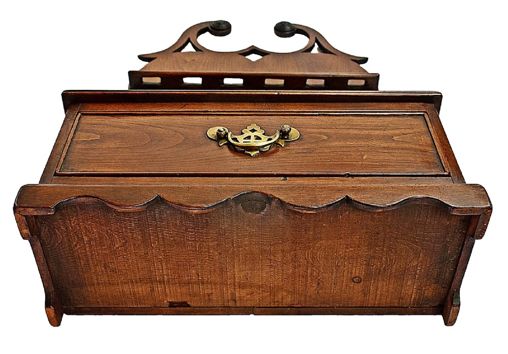 An antique carved oak spoon rack features a shaped scroll crest, a slotted rack, and a lower drawer with a brass drop handle. View VI