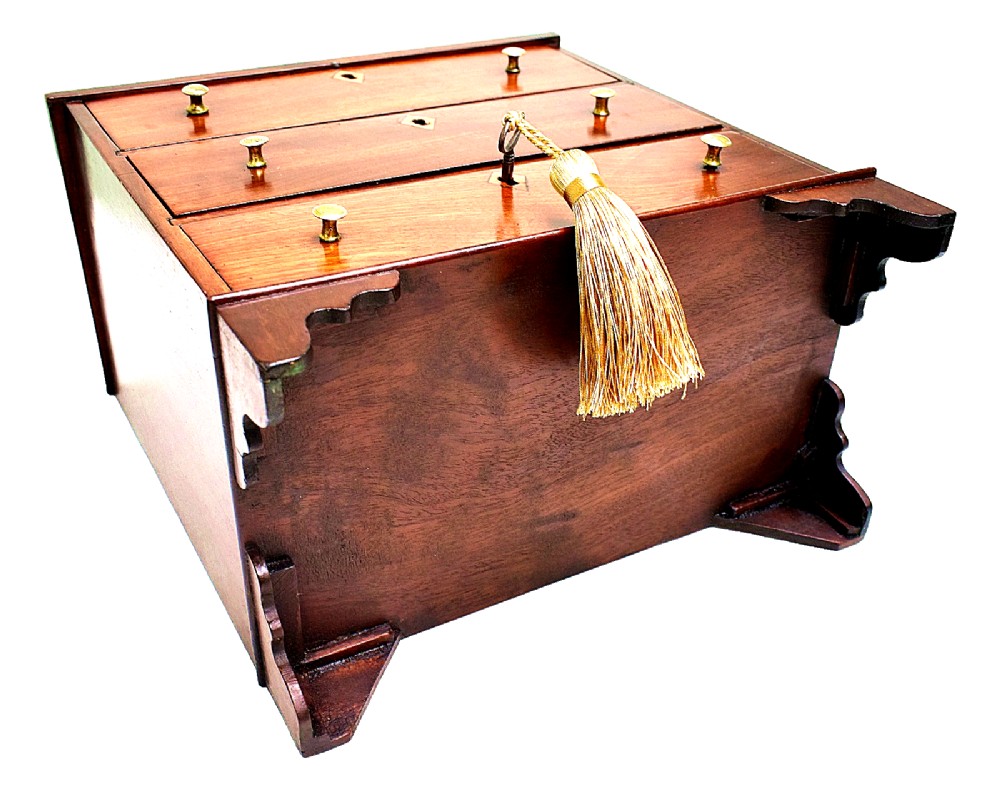 A Regency period miniature mahogany chest featuring three stacked drawers, small brass knobs, diamond escutcheons, shaped bracket feet, and a key with a tassel. View VIII