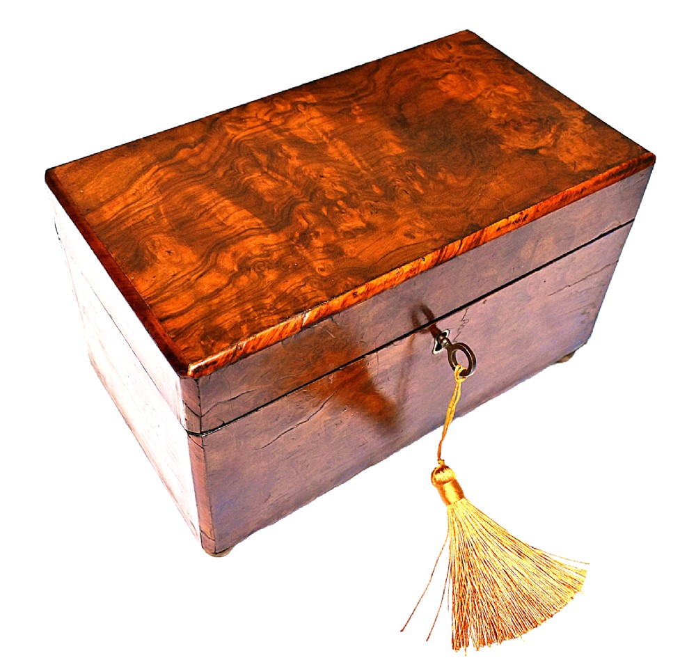 A rectangular mid-Victorian tea caddy crafted from figured burr walnut veneer with a central brass keyhole escutcheon and key.