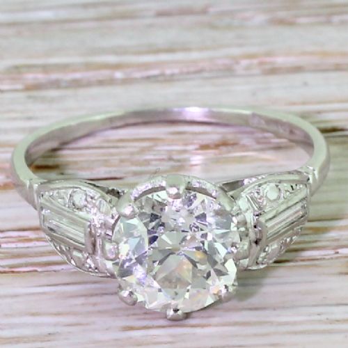 fig 1. An Art Deco platinum engagement ring featuring a central round old European cut diamond flanked by stepped geometric shoulders set with baguette and round diamonds.