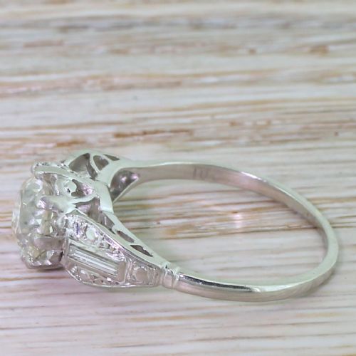 fig 2. An Art Deco platinum engagement ring featuring a central round old European cut diamond flanked by stepped geometric shoulders set with baguette and round diamonds.