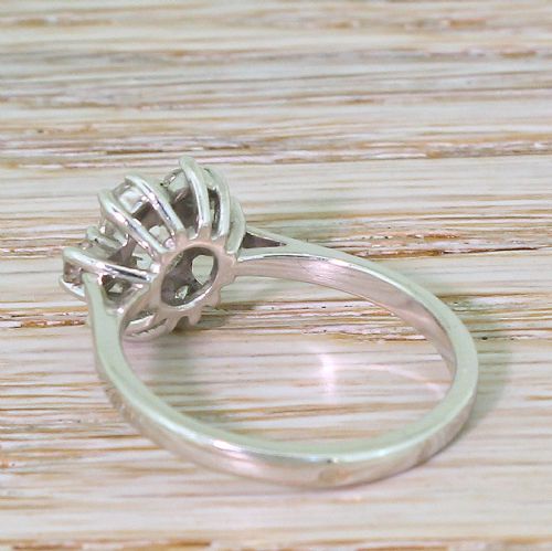 fig 3. A French mid-century white metal ring set with a central old cut diamond surrounded by a floral halo of seven smaller diamonds.