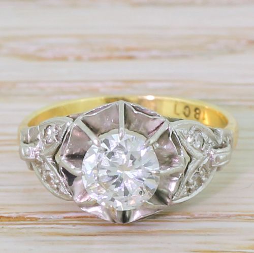 fig 1. A mid-century engagement ring featuring a transitional cut diamond set in a white metal head with carved shoulder accents on an 18ct yellow gold band.