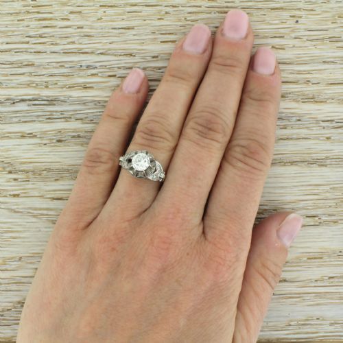 fig 4. A mid-century engagement ring featuring a transitional cut diamond set in a white metal head with carved shoulder accents on an 18ct yellow gold band.
